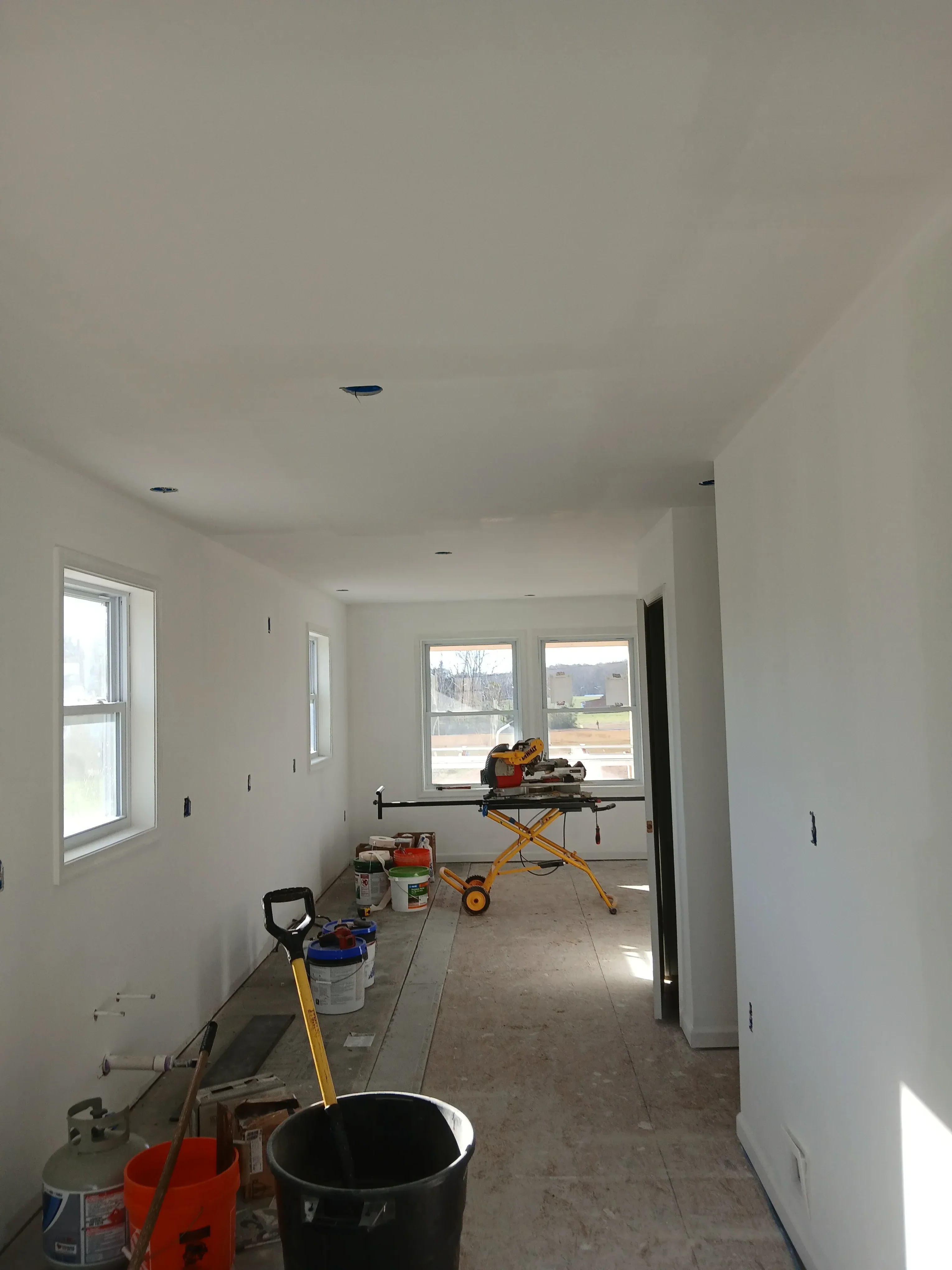 Basement renovation with white drywall, recessed ceiling lights, and new egress windows installed