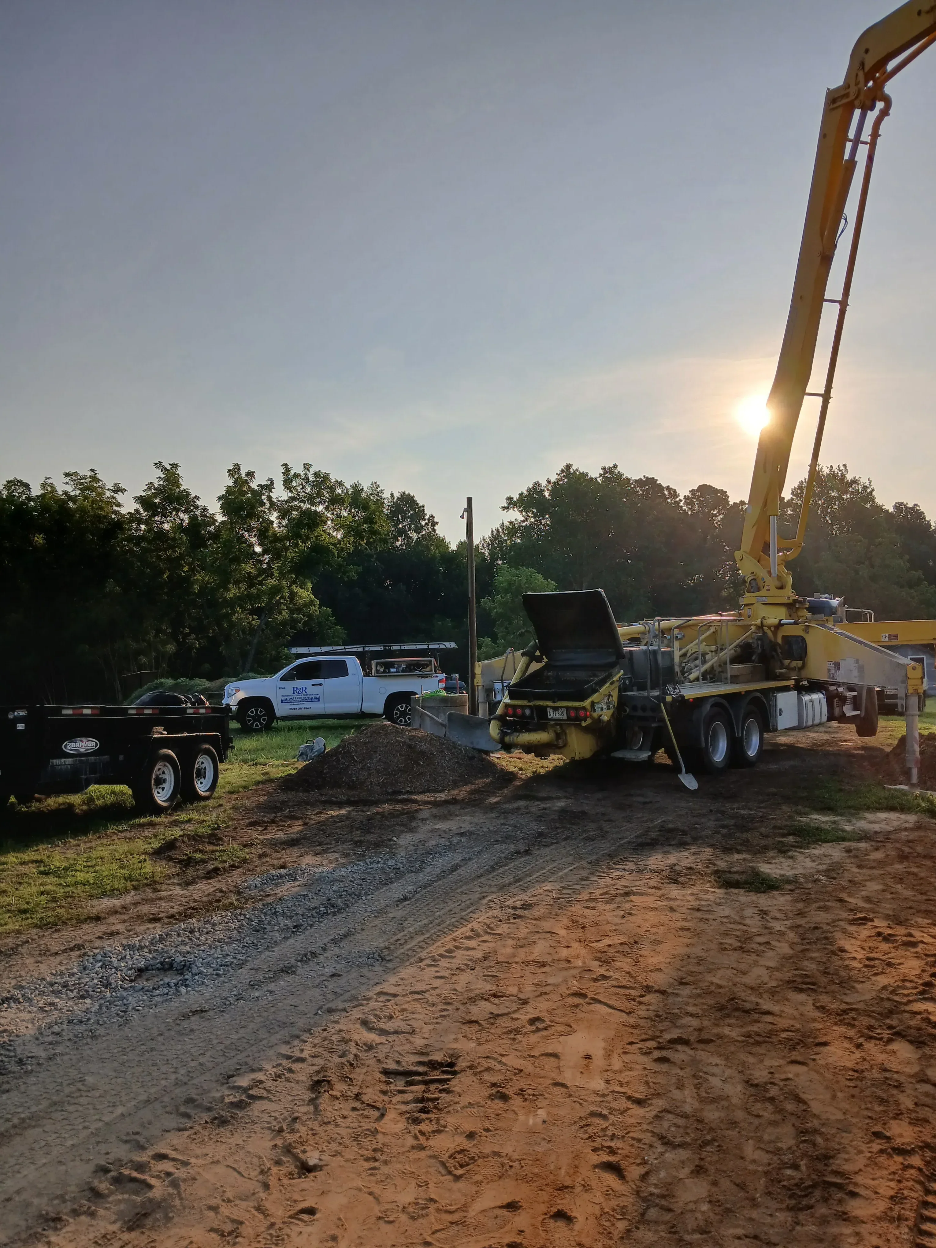 Yellow excavator with boom arm performing site excavation and grading on sloped terrain