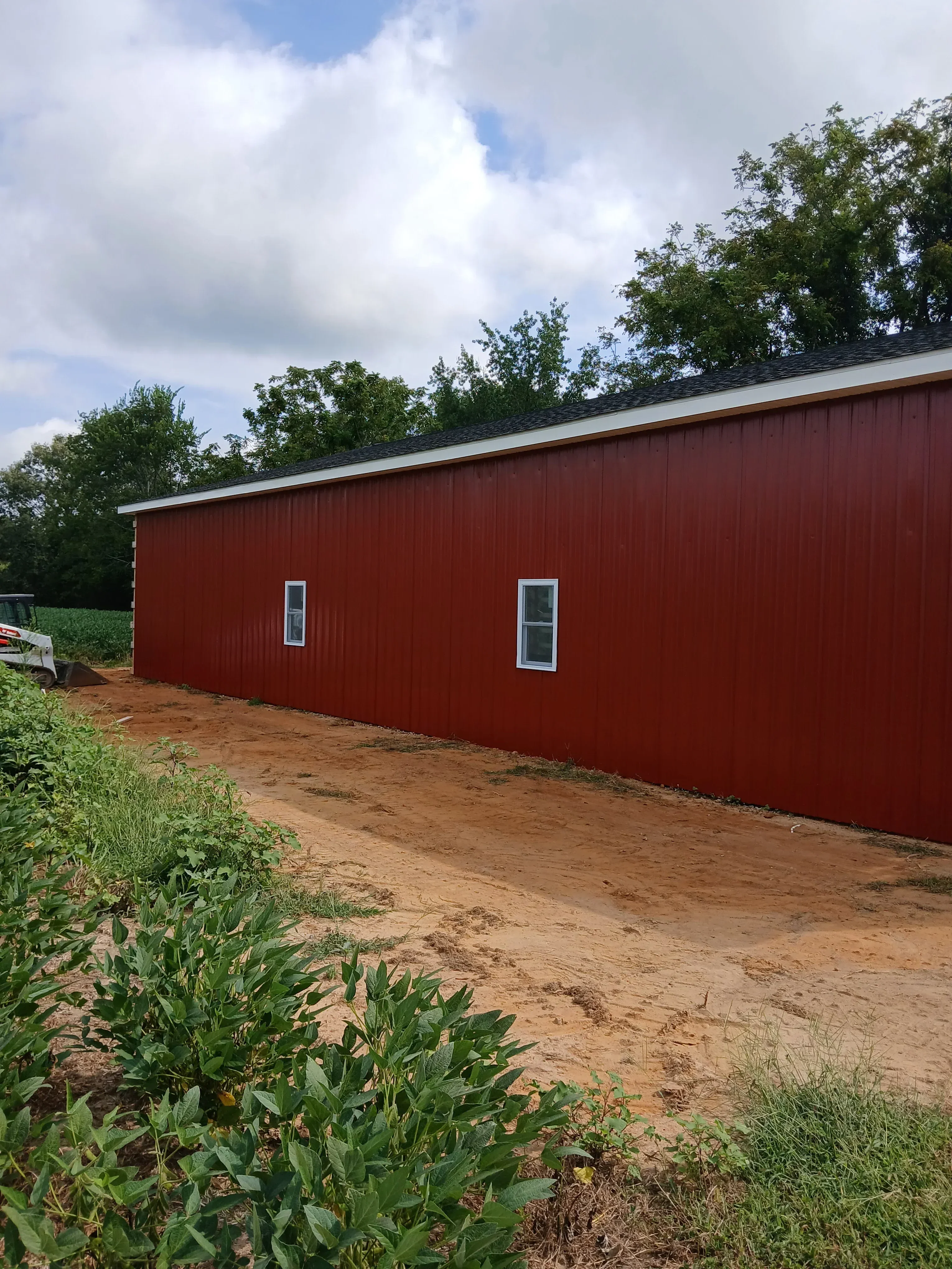 Red corrugated metal siding with two horizontal windows installed on sloped roof surface