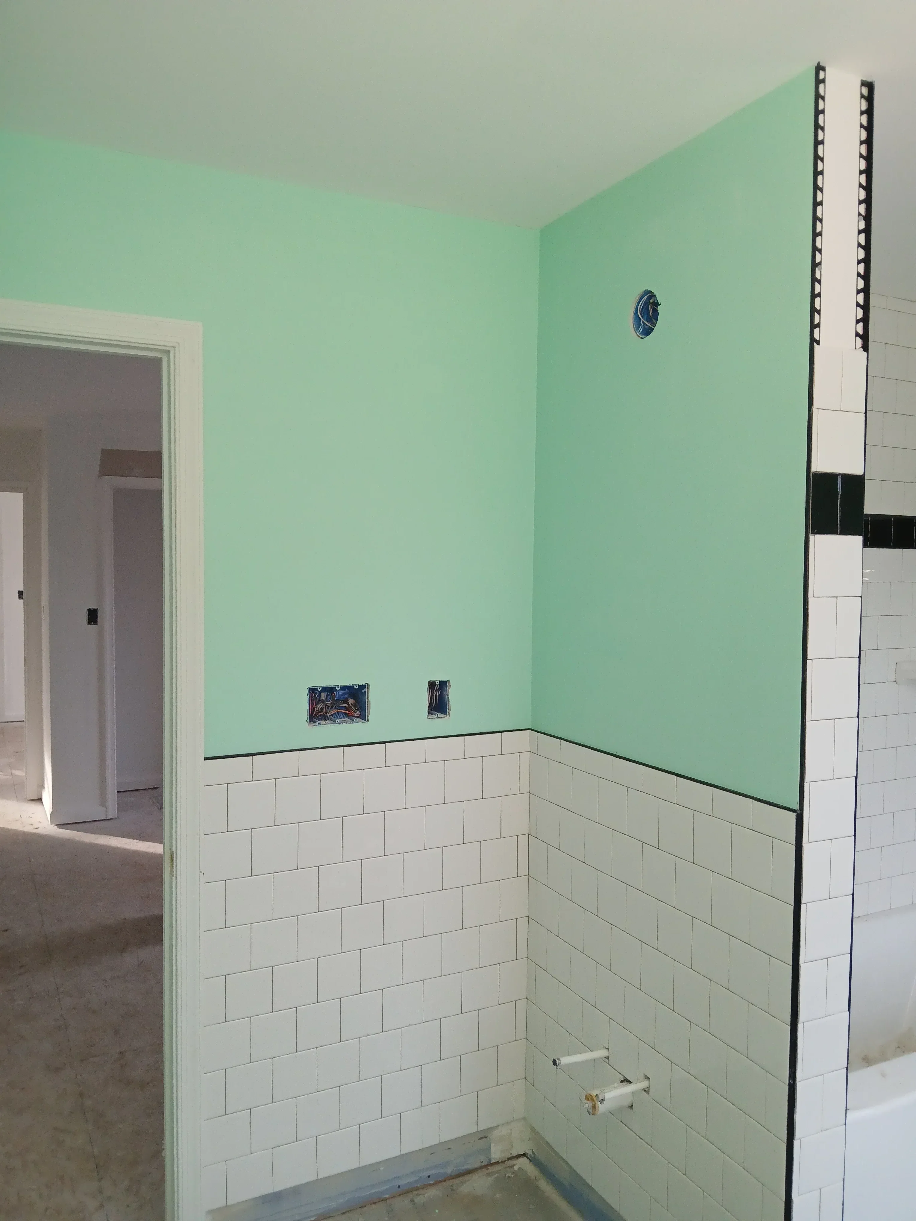Mint green drywall wall with white acoustic tile ceiling, electrical boxes visible during interior construction