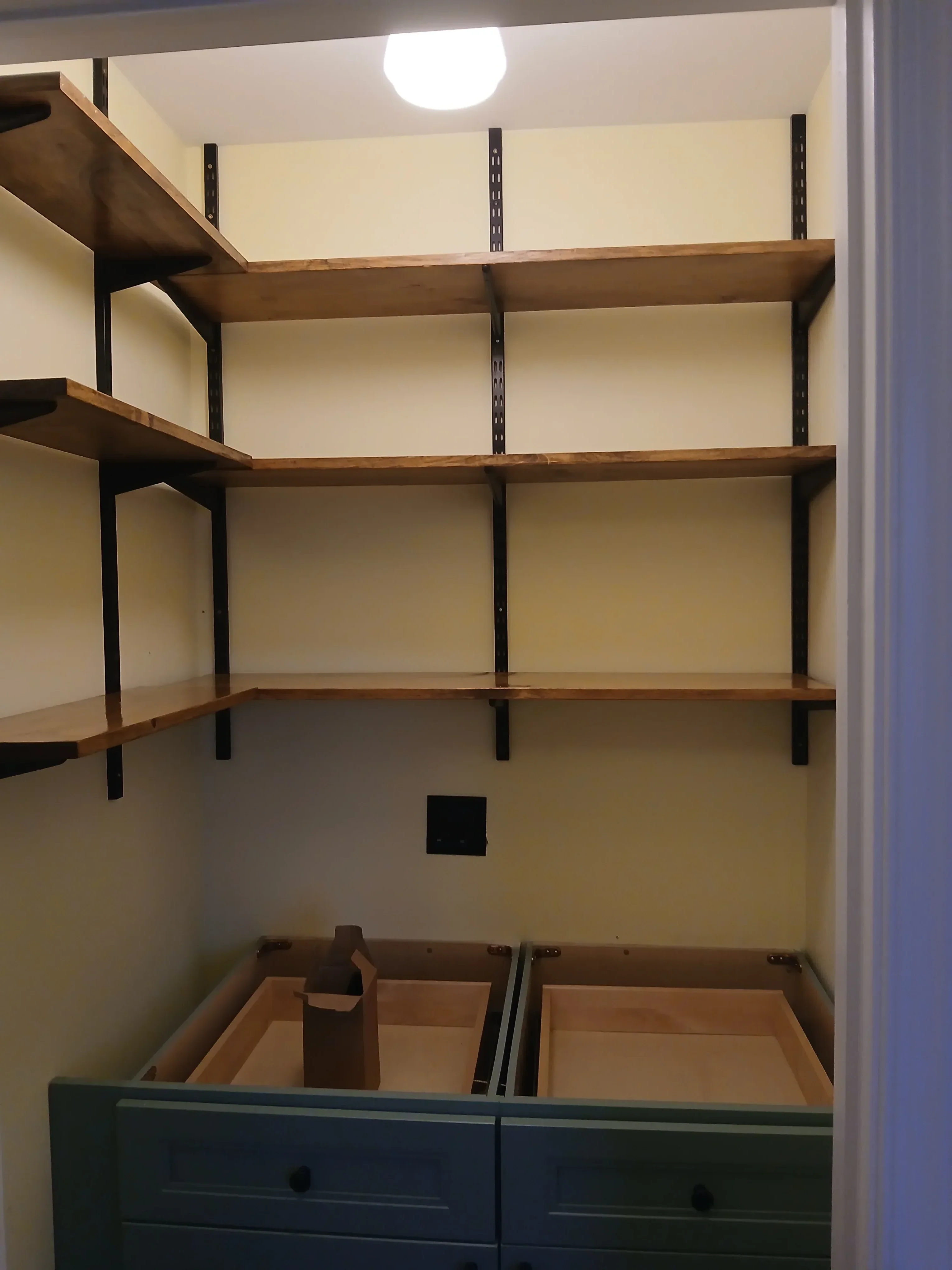 Wood-framed walk-in closet with metal brackets and built-in shelving units under construction