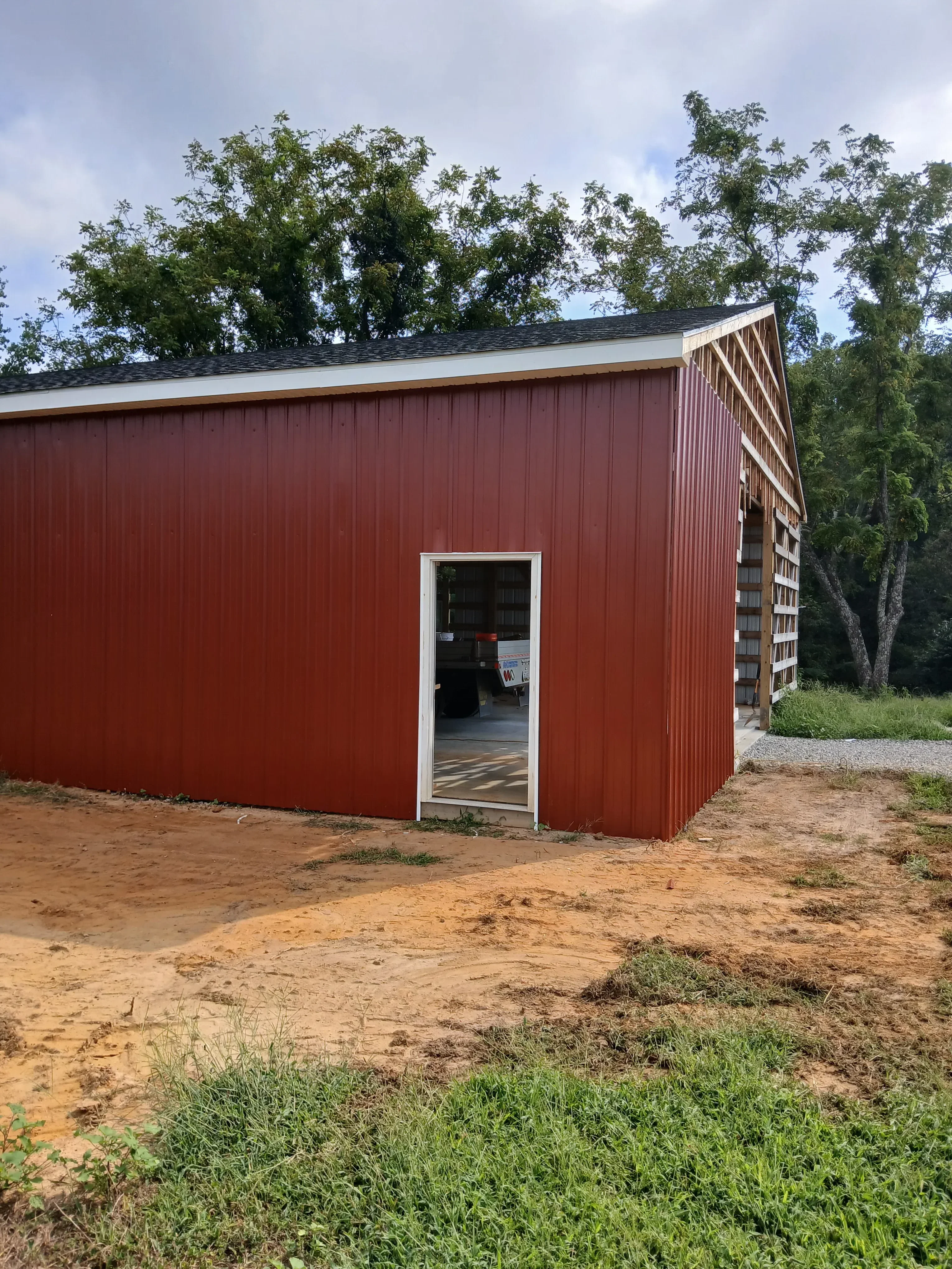 Burgundy corrugated metal siding with white trim and horizontal window installation on residential structure