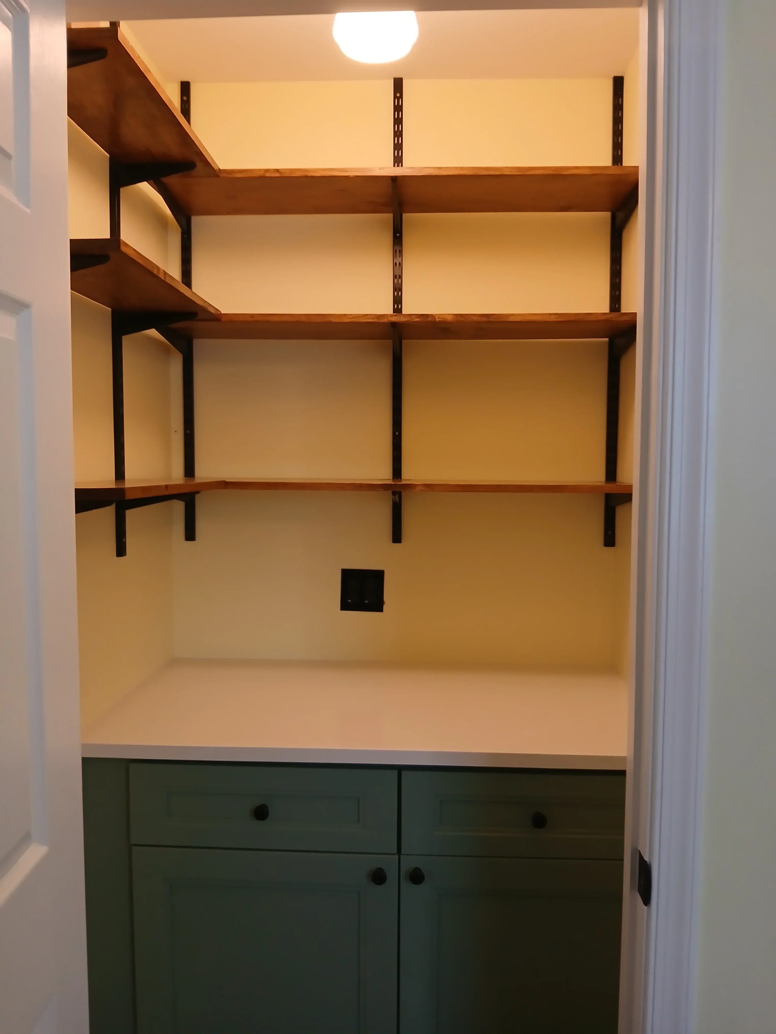 Custom wooden closet shelving with black metal brackets and integrated lighting installation