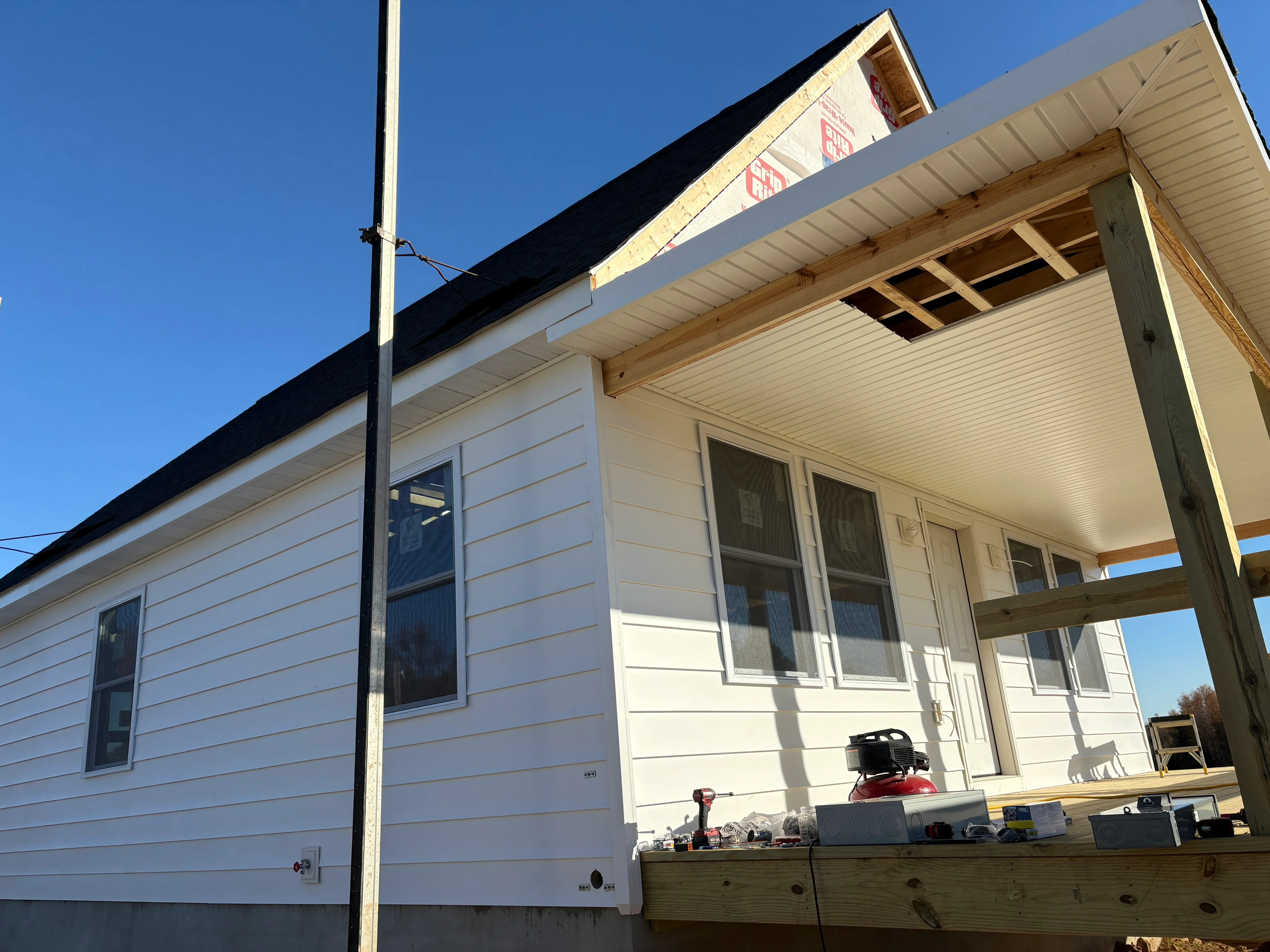 White vinyl siding, soffit, fascia, and double-hung windows on residential home with porch addition