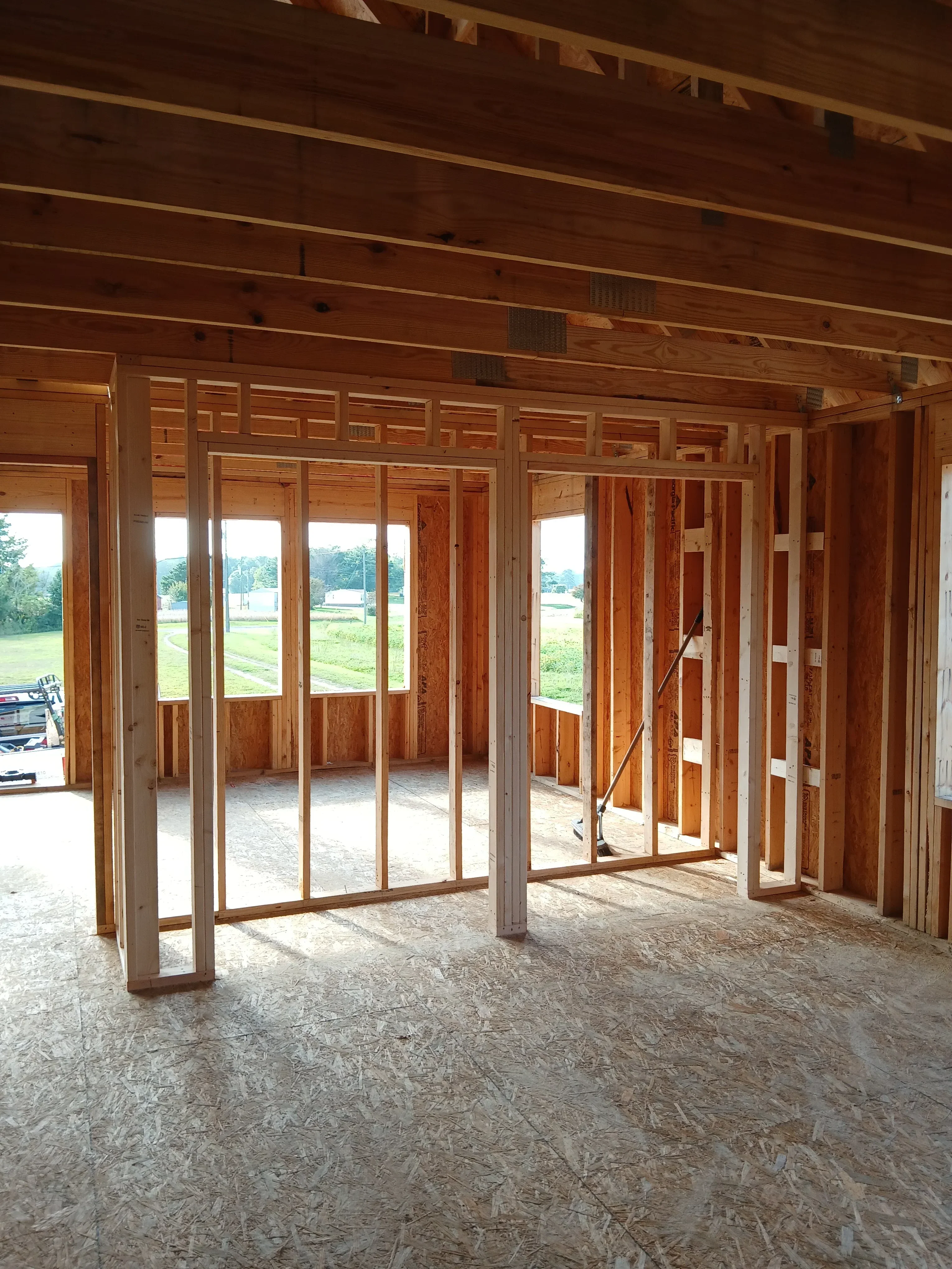 Hardwood floor installation with exposed wood beam ceiling framing and large windows