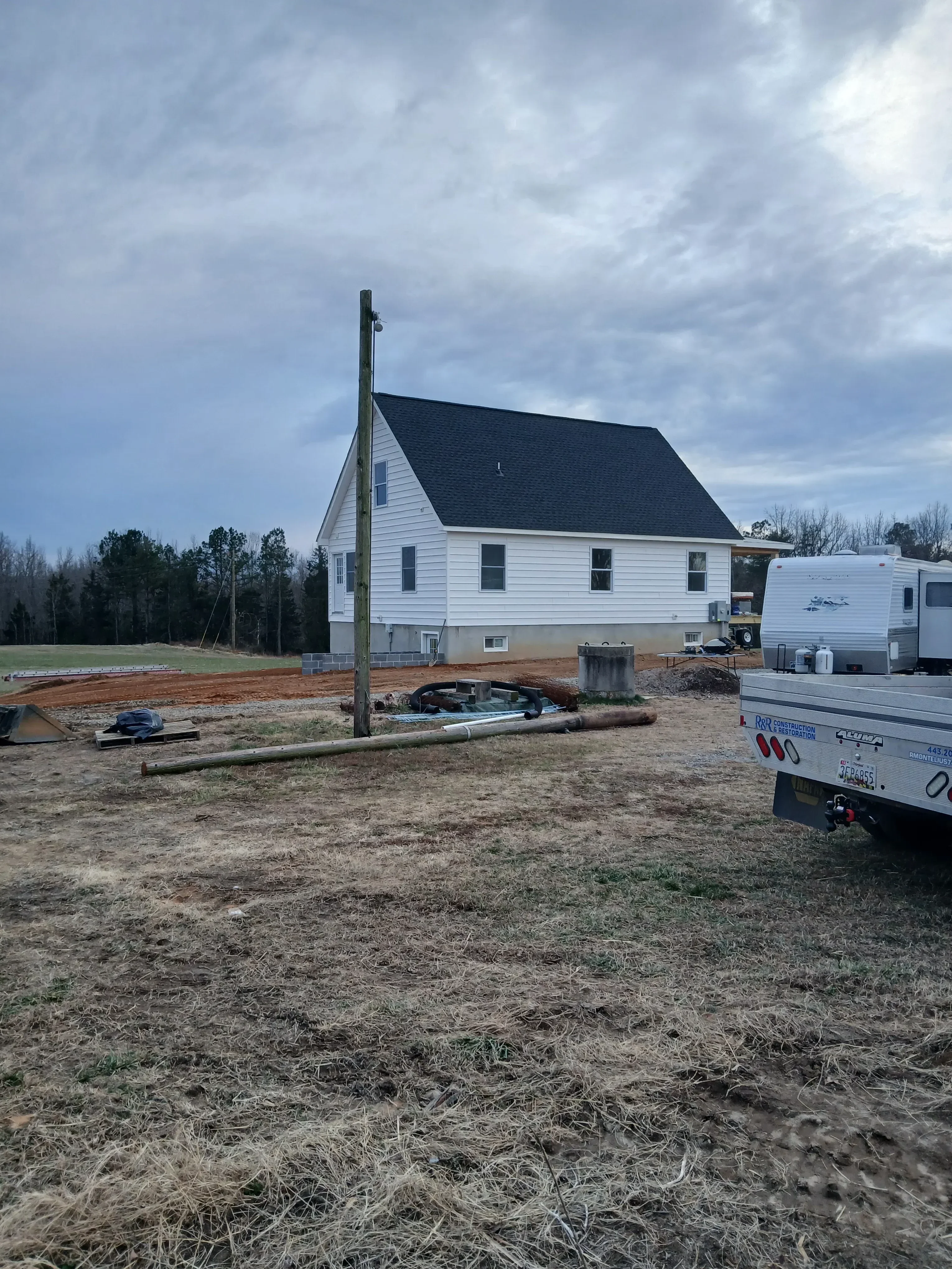 Metal standing seam roof installation with charcoal gray panels and white trim on residential home