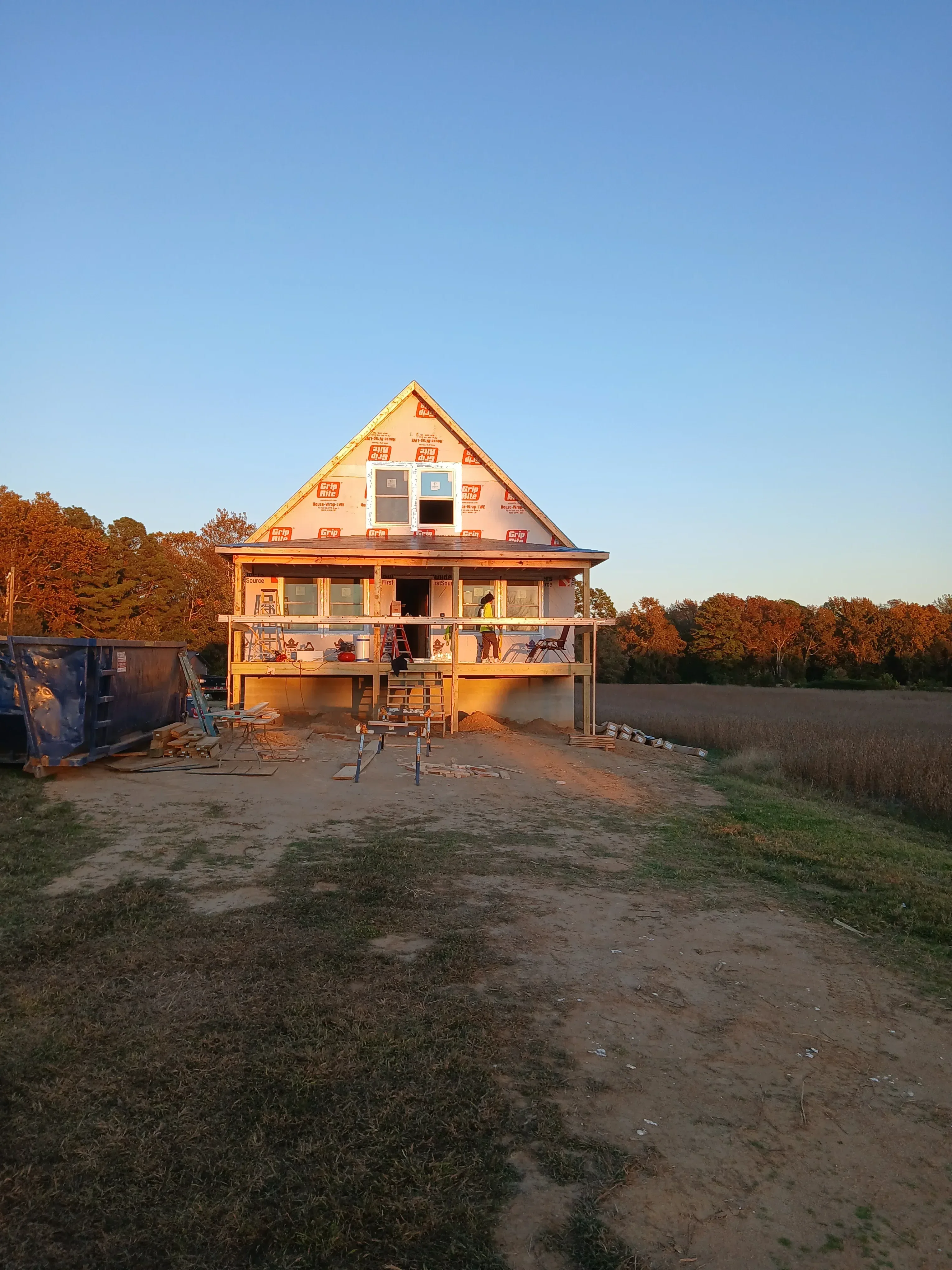 Two-story residential home under construction with brick veneer exterior and window installations