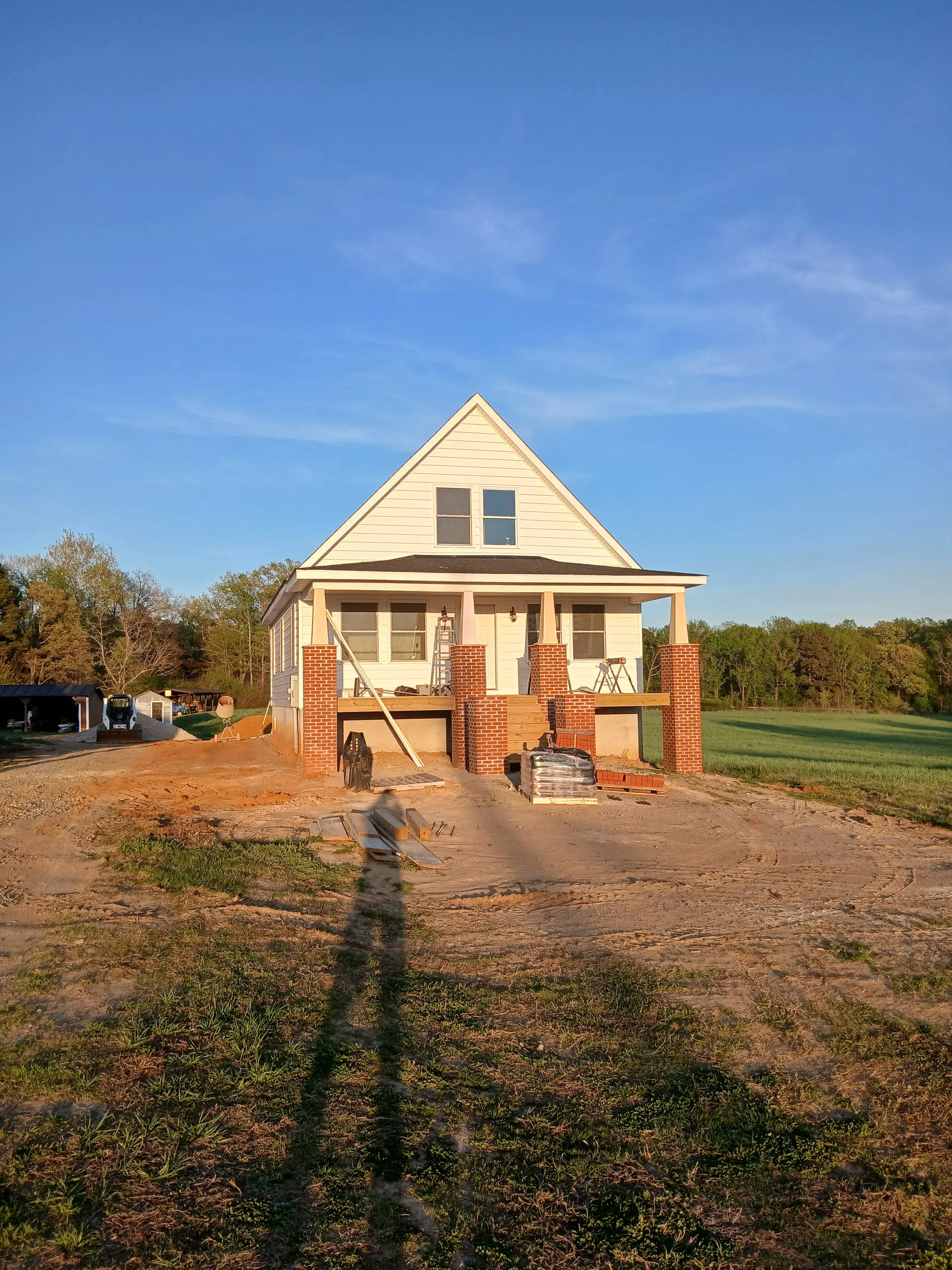 Brick residential home with metal gable roof and balconies under construction