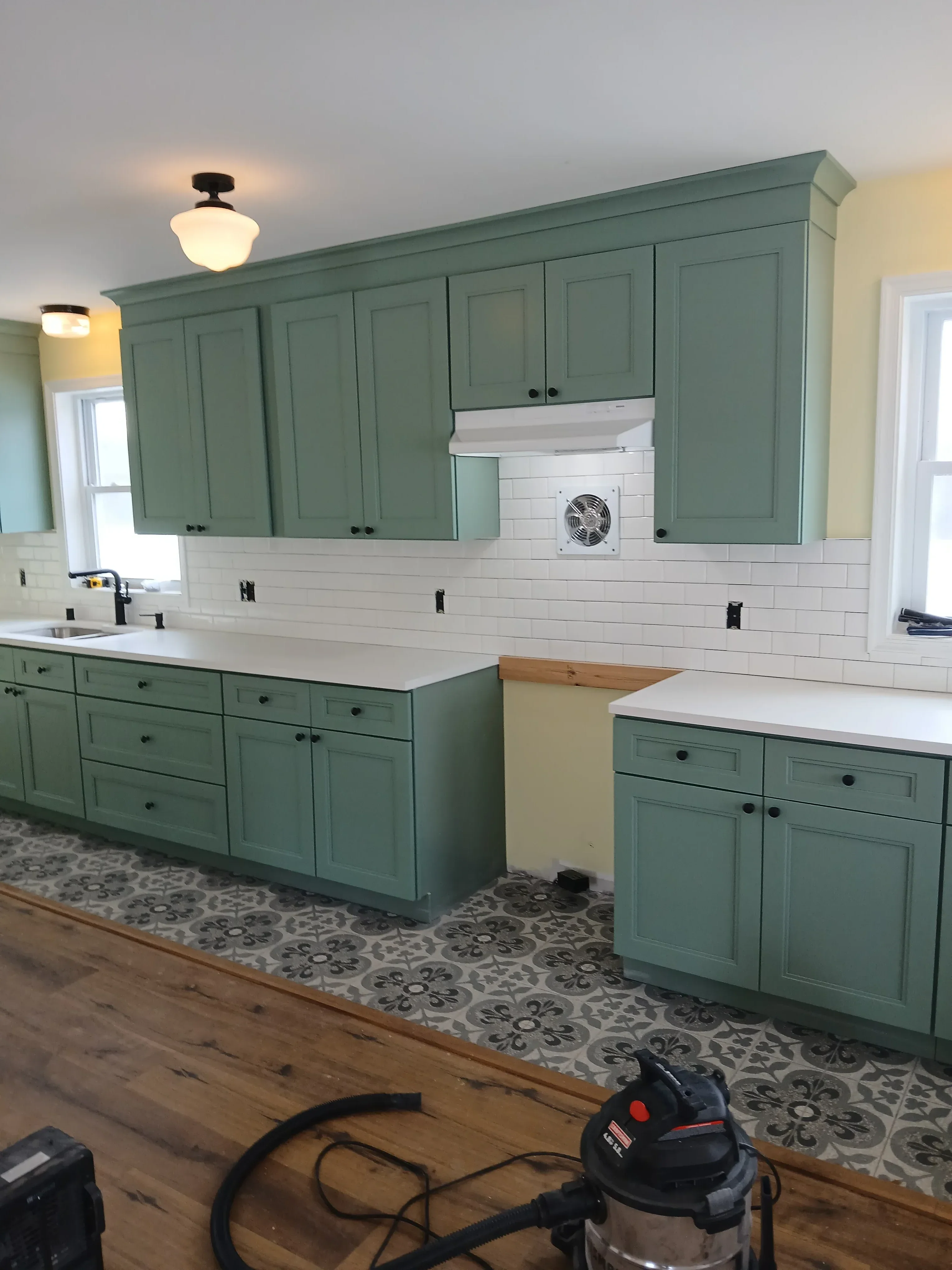 Sage green painted kitchen cabinets with black hardware and white shiplap walls