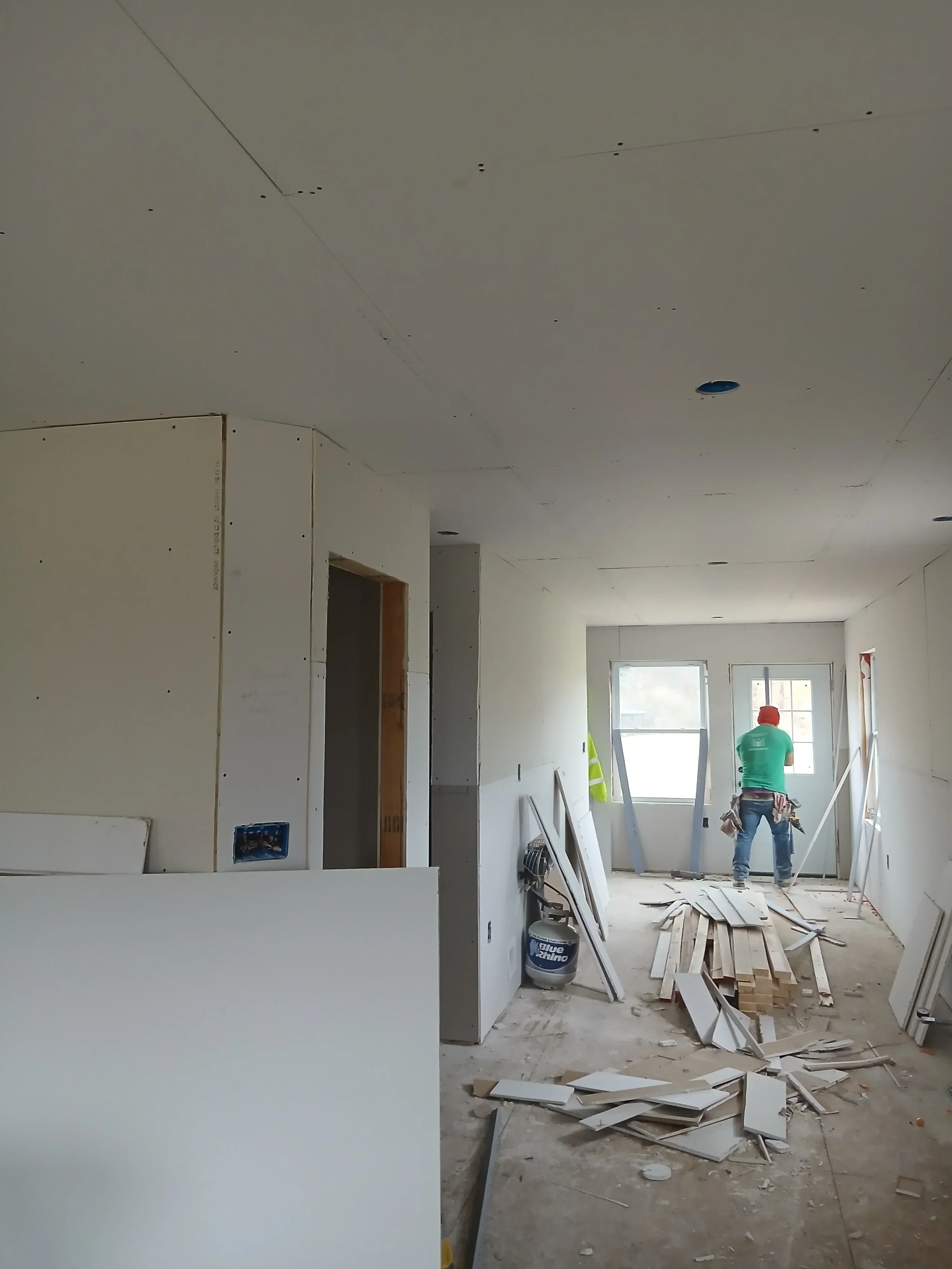 Drywall installation with framed window opening and electrical rough-in work in progress