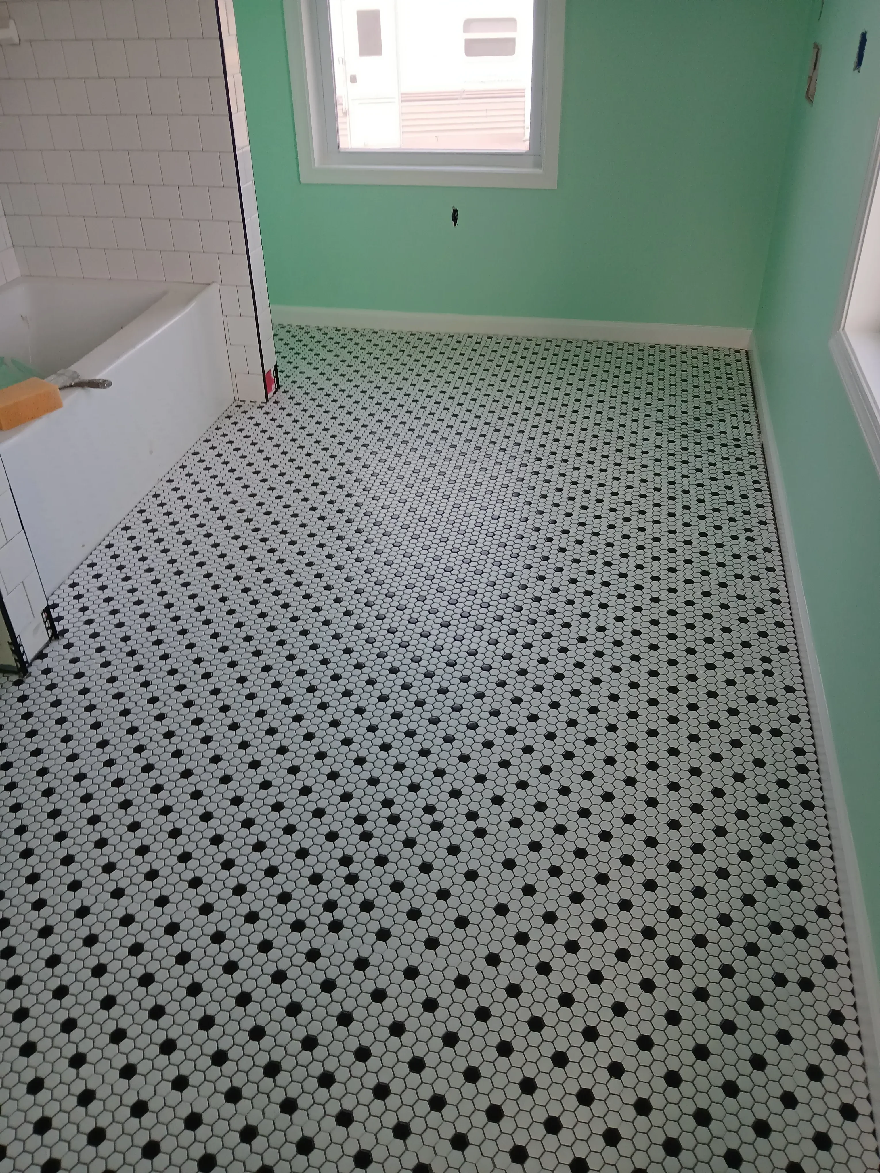 Hexagonal white mosaic tiles with black dots on shower wall, white subway tile wainscoting below