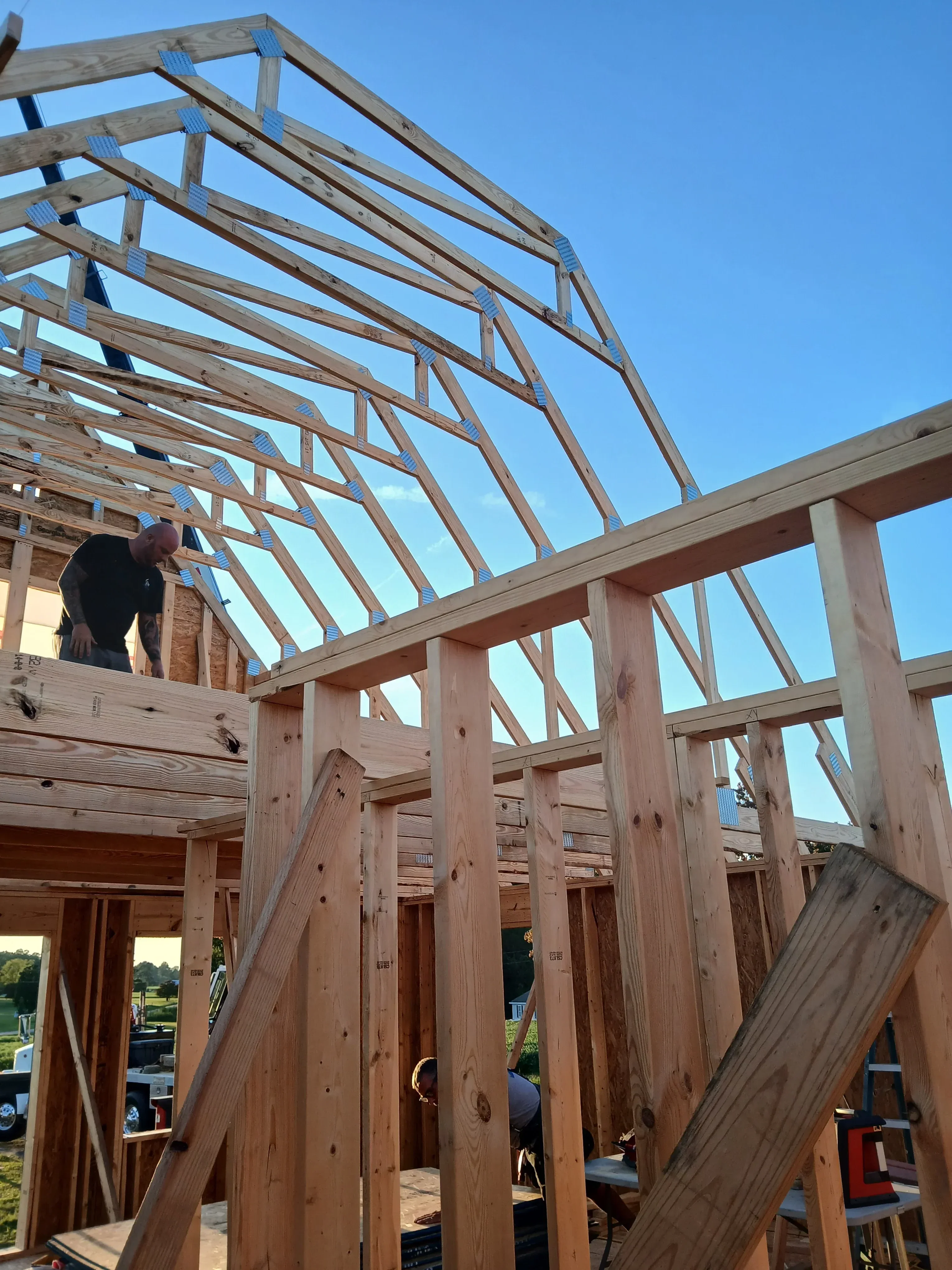 Wooden roof framing with trusses, rafters, and metal hurricane tie connectors under construction