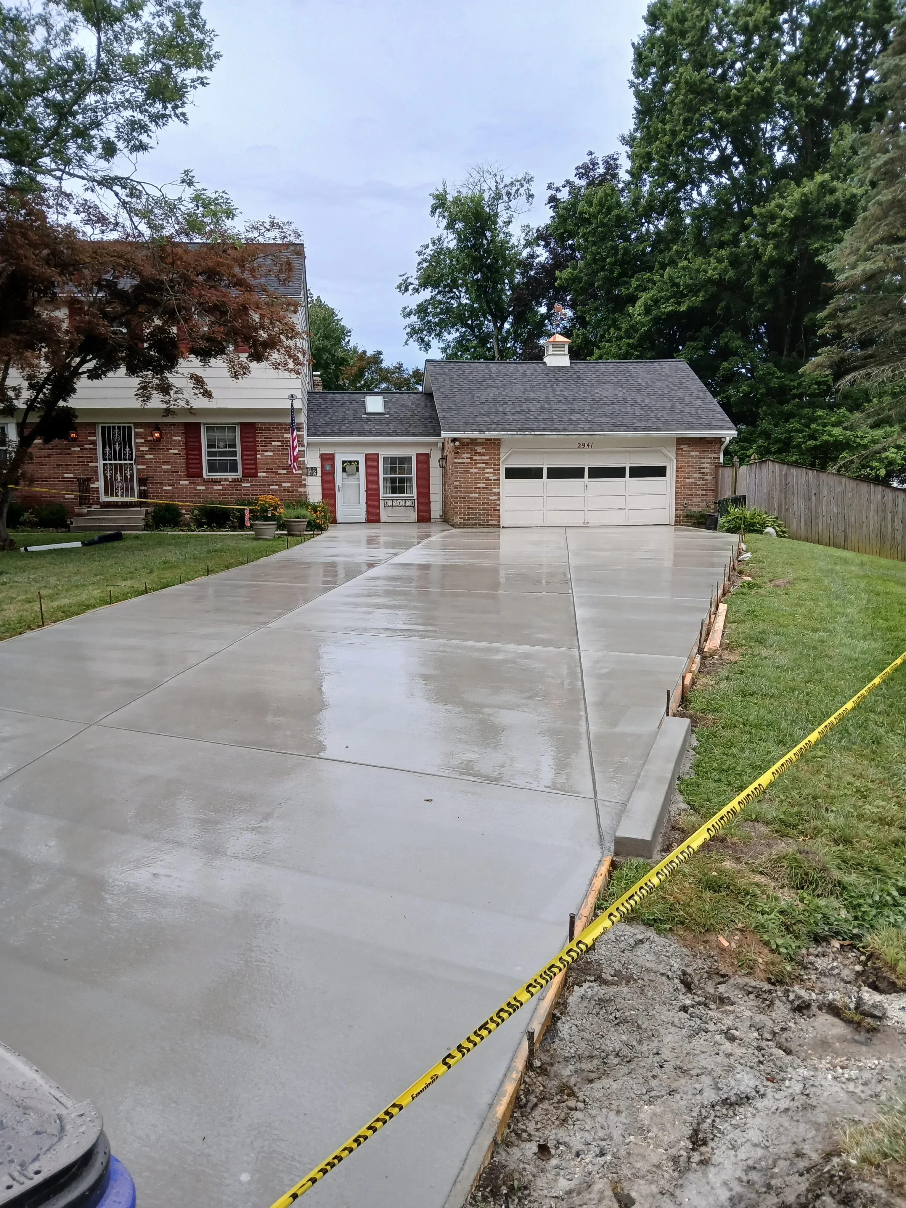 New concrete driveway with control joints installed next to brick house