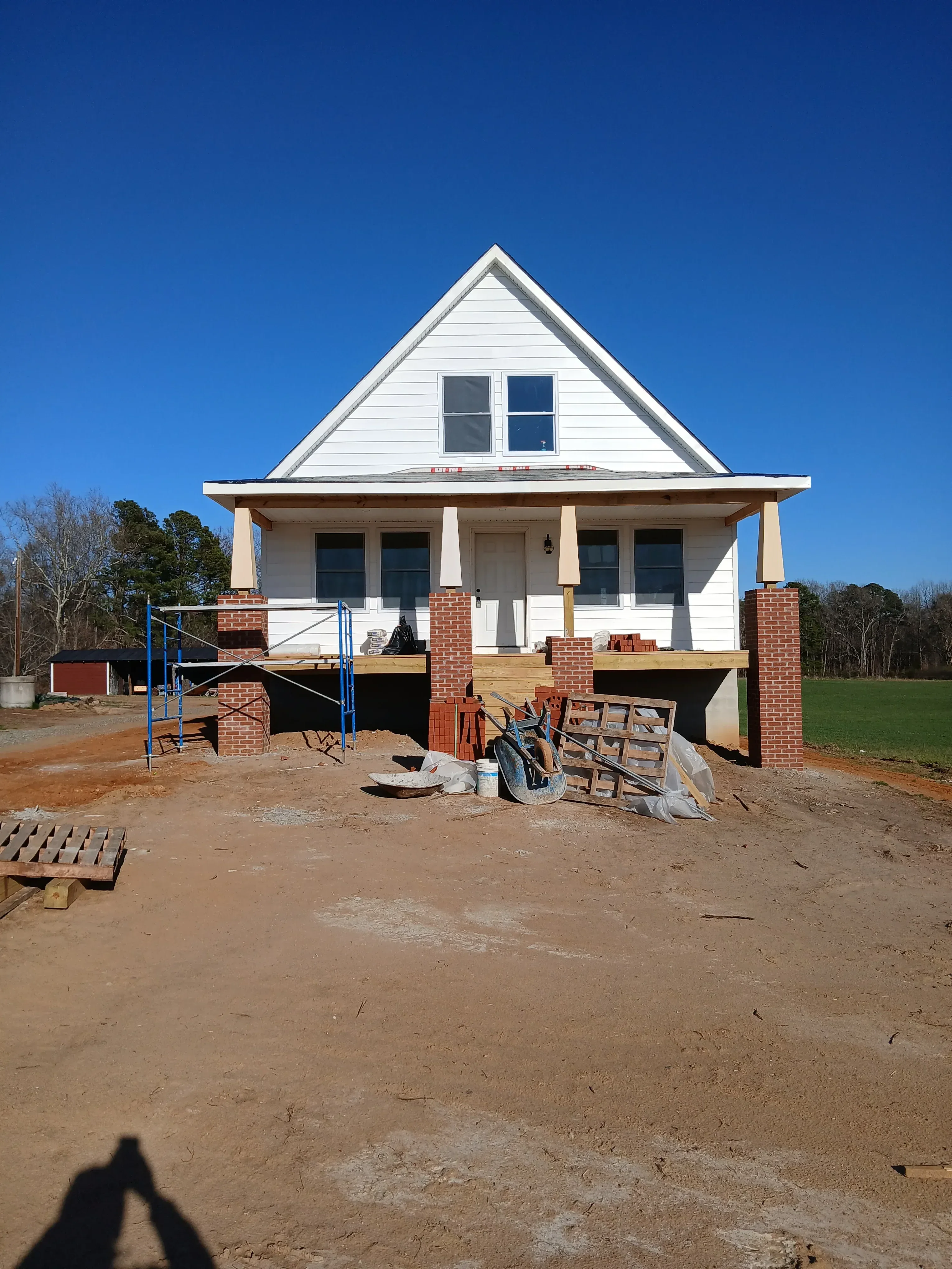 New home construction with metal roof, brick veneer, wood framing, and window openings under clear sky