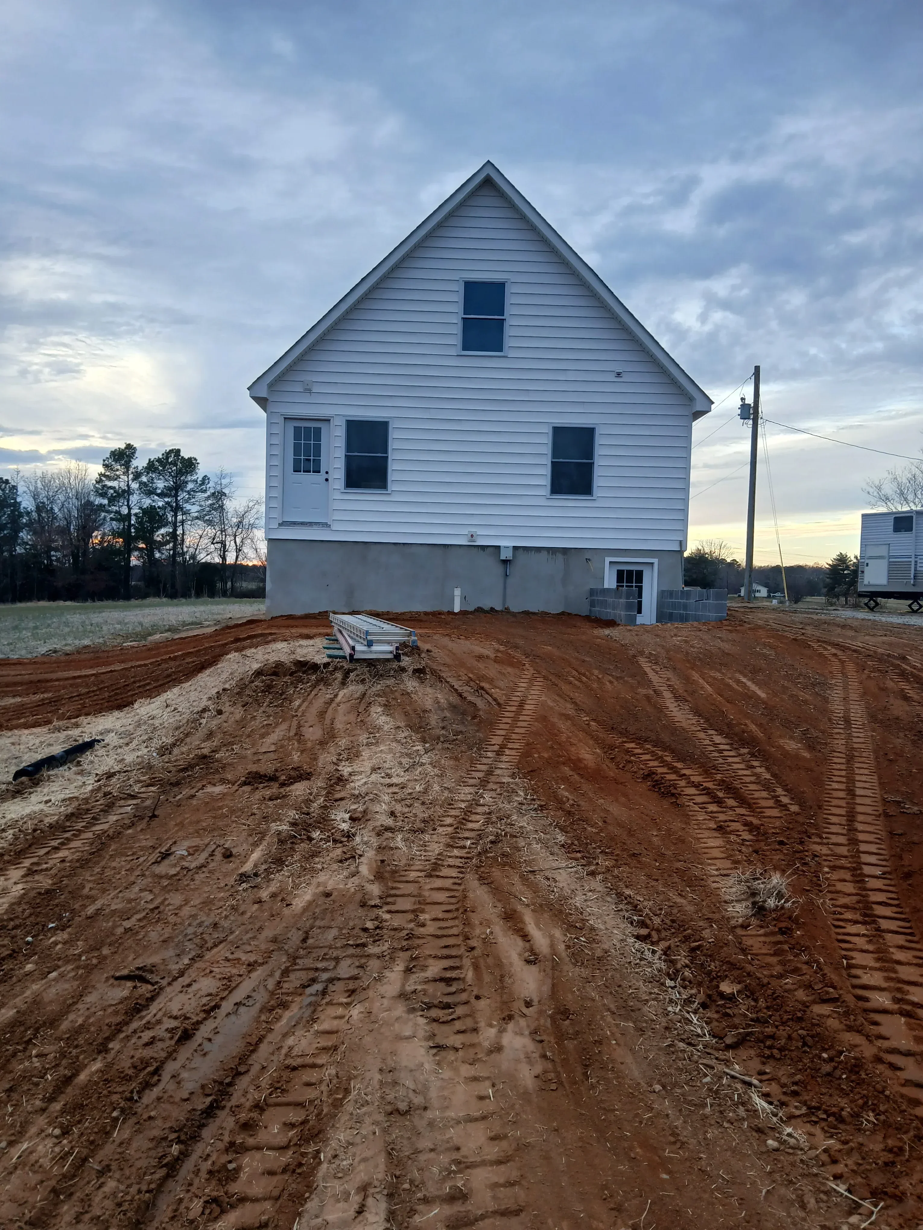 Metal building with corrugated siding, multiple windows, and prepared dirt foundation